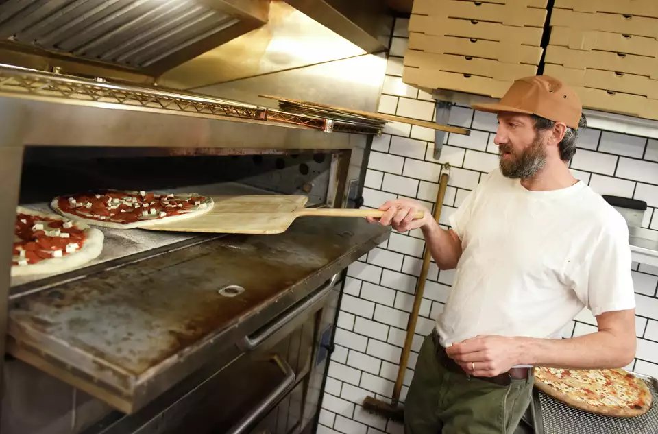Pizza going into the oven at Grigg Street Pizza, fresh pies on the peel